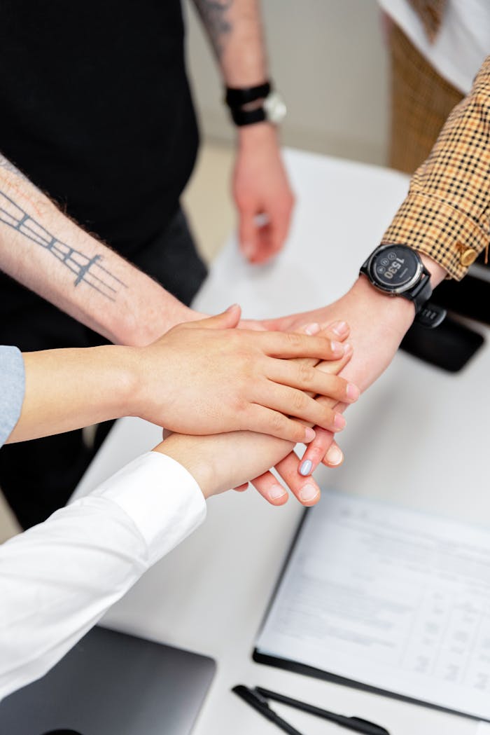 Close-up of a diverse team stacking hands on an office desk, symbolizing teamwork.